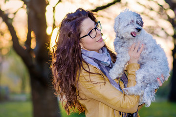Beautiful Smiling Woman Hugging  Her Cute  Dog in the Park .Pet and Owner Outdoor in the Nature