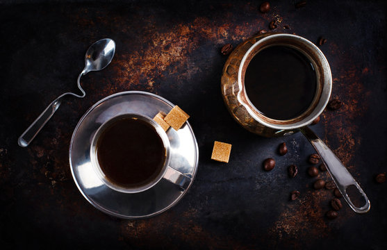 Cup of black coffee with sugar cubes and a cezve