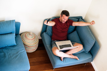 Successful entrepreneur celebration victory while using laptop at home