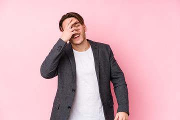 Young caucasian business man posing isolated blink at the camera through fingers, embarrassed covering face.