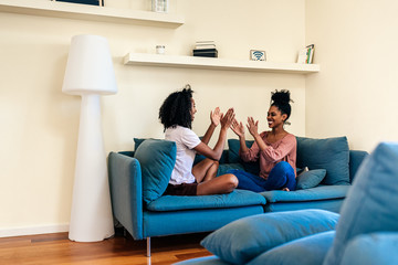 Pleased black females playing had clap game on sofa
