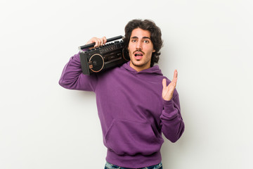 Young urban man holding a guetto blaster surprised and shocked.