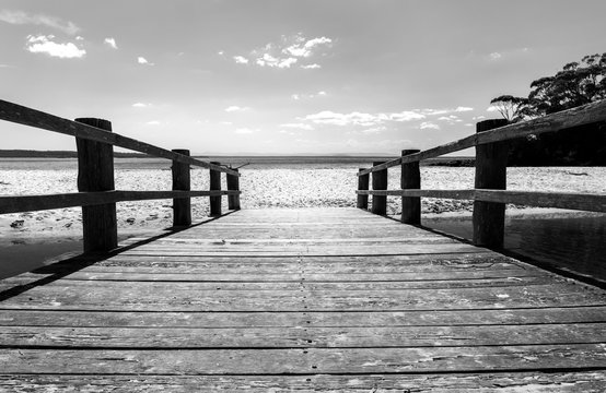 Black and white photo of a wooden bridge to the ocean, Jervis Bay Australia