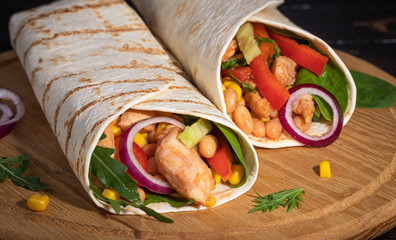 Burritos wraps with chicken and vegetables on dark background. Mexican food
