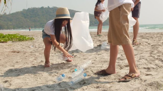 Asian young happy family activists collecting plastic waste on beach. Asia volunteers help to keep nature clean up and pick up garbage. Concept about environmental conservation pollution problems.