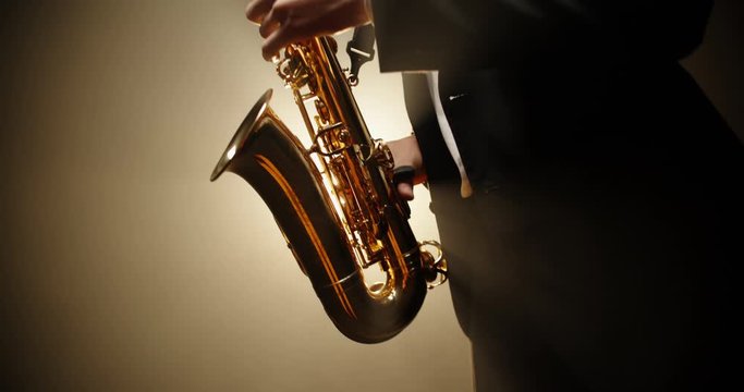 A saxophonist wearing a suit performing a solo on stage, spotted and silhouetted by light - arts, jazz music concept 4k footage