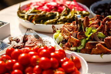 Small red cherry tomatoes spill out of a wicker basket on an old wooden table in rustic style, selective focus