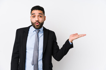 Young latin business woman against a white background isolated impressed holding copy space on palm.