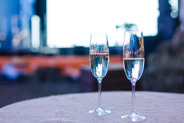photo of two champagner glasses on glass table with bokeh background