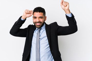 Young latin business woman against a white background isolated celebrating a special day, jumps and raise arms with energy.