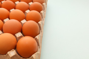 Brown cage free chicken eggs in carton, close up on blue background. easter card