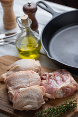 fresh chicken thigh on wooden cutting board