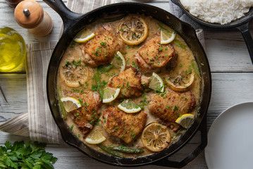 lemon butter chicken in iron skillet with cooked rice