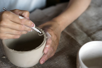 Female hands hold a bowl for casting clay products. Shaped method for making clay dishes. Handwork....