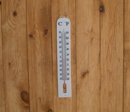  white plastic thermometer hanging on a wooden wall