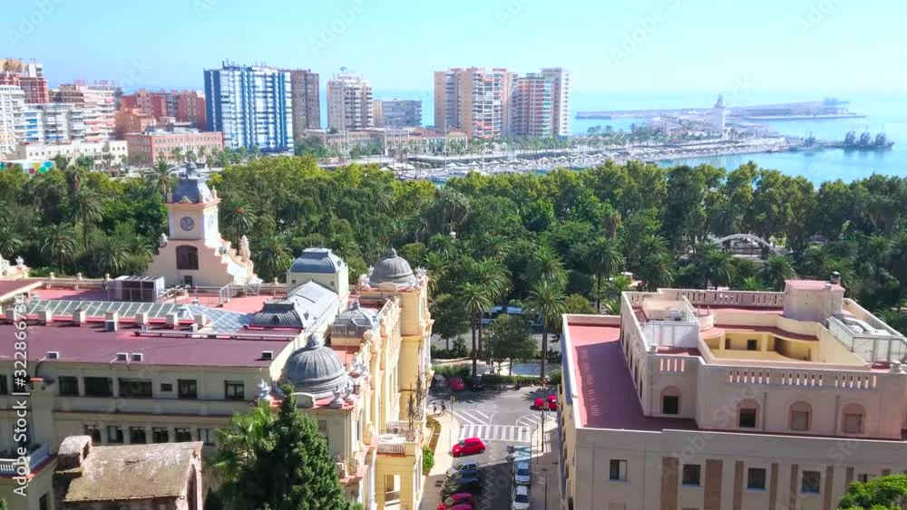 Poster MALAGA, SPAIN - SEPTEMBER 26, 2019: The cityscape with clock tower of Town Hall, lush green Malaga park and modern district on the background, on September 26 in Malaga