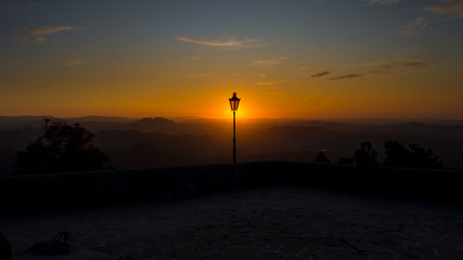 A lamp post in a square during beautiful colorful sunset viewed from a square on top of San Marino city