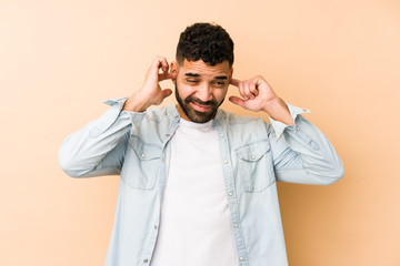 Young mixed race arabic man isolated covering ears with hands.