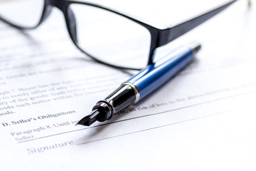 Signing the contract with pen and glasses in business work on office desk