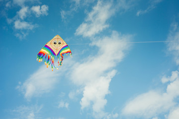 Colorful kite flying against the blue sky with clouds