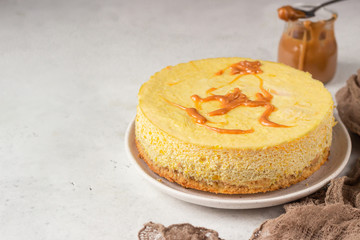 Pumpkin cheesecake with caramel sauce, light grey stone background. Selective focus. 