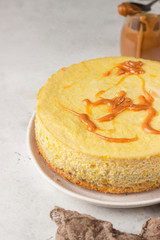 Pumpkin cheesecake with caramel sauce, light grey stone background. Selective focus. 