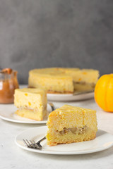 Plate with slice of pumpkin cheesecake and with caramel sauce, light grey stone background. Selective focus. 
