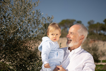 Fototapeta premium Grandfather with his grandson in his arms in nature
