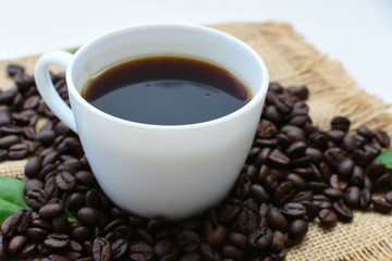 Coffee beans, accompanied by cup of hot coffee