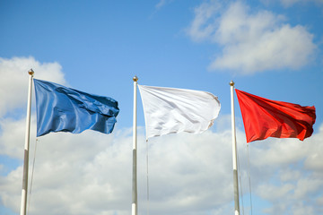 The three flags (blue, white, red) on blue sky - 322869924