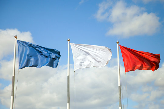 The three flags (blue, white, red) on blue sky