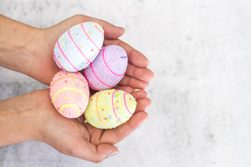 Painted boiled eggs in female hands close-up on a white background.