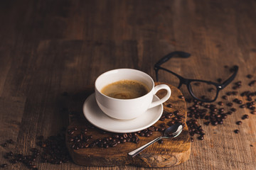 cup of coffee with beans on wooden table