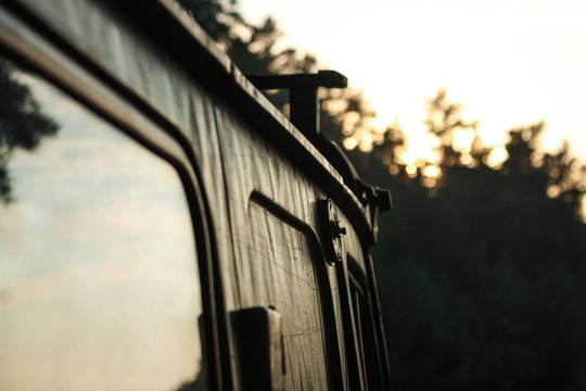 old car among the forest trees at sunset