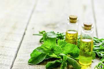 cosmetic oil in bottle with herbs on light table background