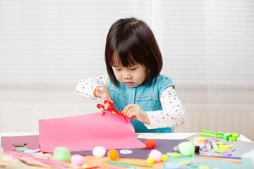 toddler girl learn making  Origami at home against white background