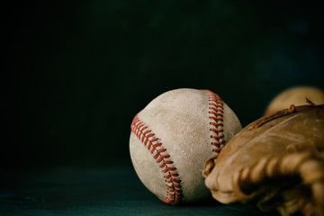 Old baseball ball with brown glove closeup, black background for sports text space.
