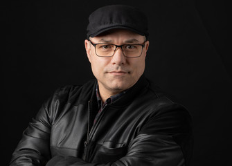 portrait of a middle aged man in black hat on dark background