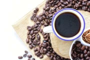 Coffee beans, accompanied by cup of hot coffee