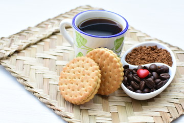 Coffee beans, accompanied by cup of hot coffee and cookies