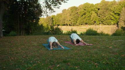 Flexible young couple doing different asanas practising yoga training class together in the morning...