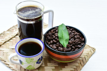 Coffee beans, accompanied by cup of hot coffee