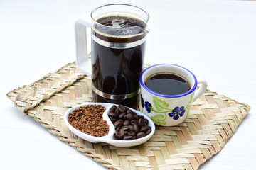 Coffee beans, accompanied by cup of hot coffee