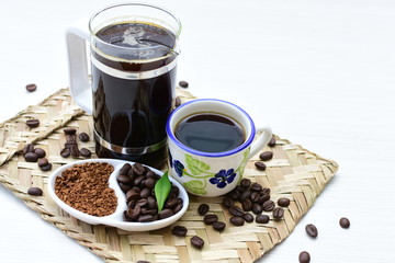 Coffee beans, accompanied by cup of hot coffee