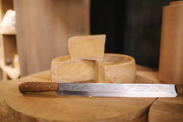 Cheese with knife of wooden board in cheese shop