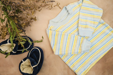 Striped shirt and booties for newborn boy. Baby's clothes and bouquet of flowers. Expecting a baby. Flatlay design.