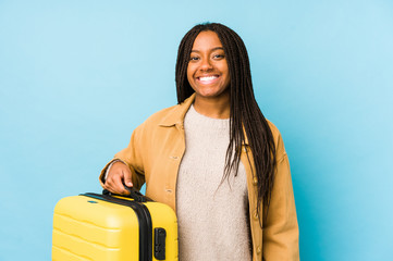 Young african american traveler woman holding a suitcase isolated happy, smiling and cheerful.