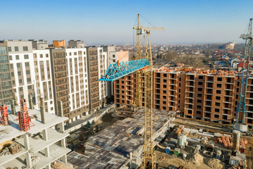 Fototapeta premium Construction and construction of high-rise buildings, the construction industry with working equipment and workers. View from above, from above. Background and texture