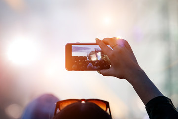 Fan at outdoor music festival taking pictures and making videos using his smartphone.