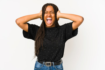 Young african american woman isolated on white background covering ears with hands trying not to hear too loud sound.